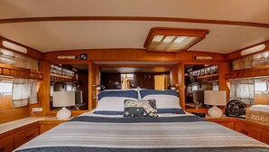A cozy, well-lit bedroom with a large bed, wooden walls, and a skylight. - Spacious & Comfy 2BR/2Bath Yacht -Toasty Heat- On Freedom Trail-Walk to Downtown (Boston)