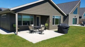 A modern house with a covered patio, a barbecue grill, and a large window.