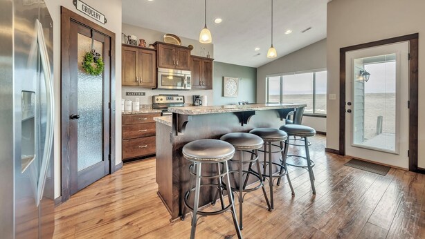 A modern kitchen with wooden cabinets, stainless steel appliances, and a bar area with stools.