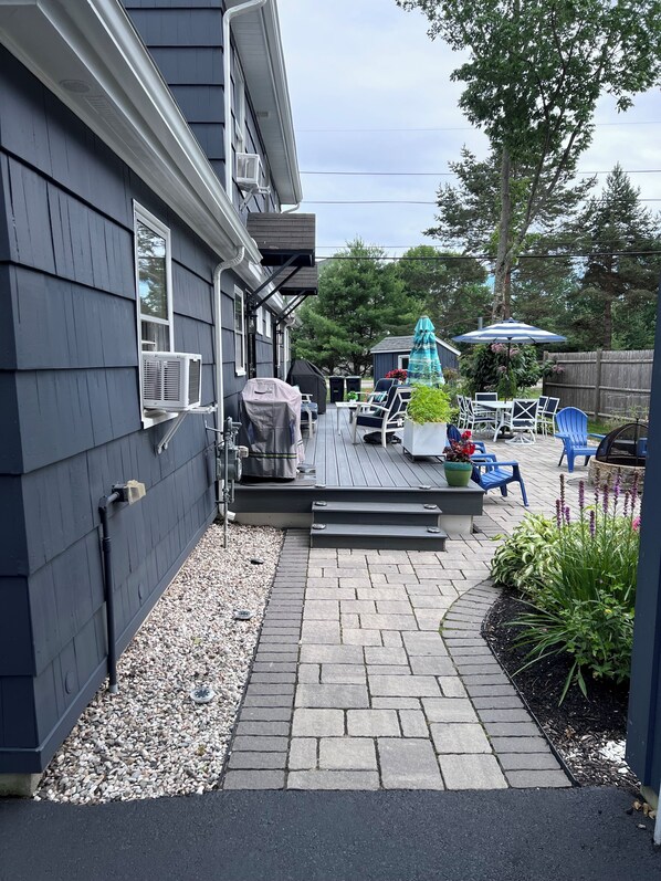 Un espace patio aménagé avec un barbecue, du mobilier d’extérieur et une table couverte.