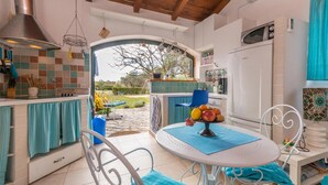 Una cocina con comedor, vista al jardín y un refrigerador blanco.