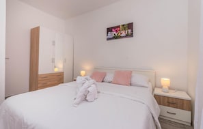 A neatly arranged bedroom with a bed, bedside tables, a wardrobe, and a wall-mounted artwork.