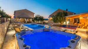 Un patio trasero con dos jacuzzis, una piscina y mobiliario exterior.