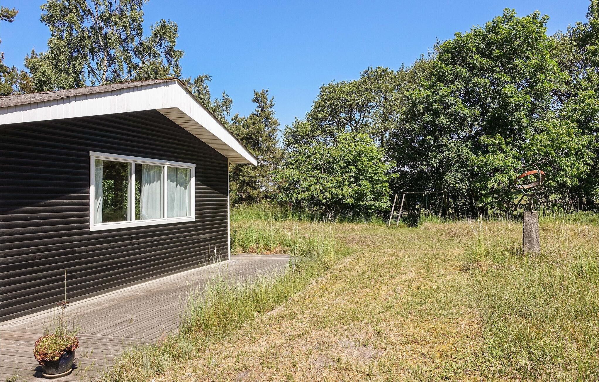 Une cabane de plain-pied, à l’extérieur sombre, avec une fenêtre blanche et un petit porche.