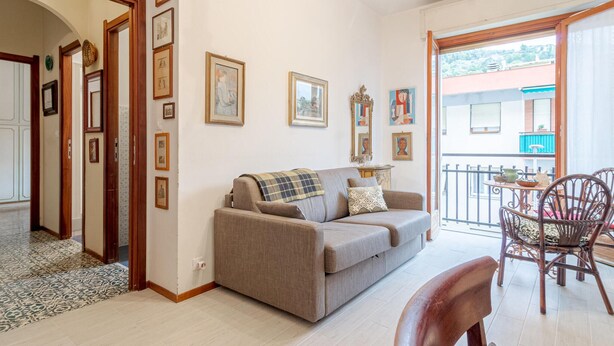 Ein Wohnzimmer mit Sofa, einem Esstisch mit Stühlen und einem Balkon mit Geländer.