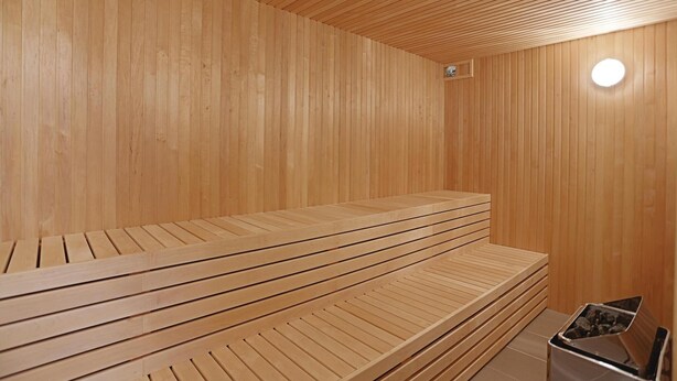 Una sauna in legno con panche e un piccolo riscaldatore.