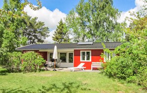 A red and white house with a patio, a white umbrella, and a lounge chair.