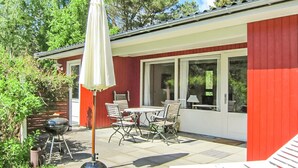 A patio with a table and chairs, a grill, and a white umbrella. - Awesome home in Aakirkeby with kitchen (Aakirkeby)
