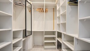Armadio a tutta parete con scaffali multipli e spazio per appendere, dotato di specchio e porta appendiabiti in legno.