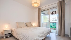 Una camera da letto con un letto, comodini, una lampada e vista su un balcone.