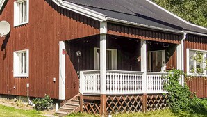Une maison en bois à deux étages, dotée d’un porche, d’une antenne parabolique et d’un petit escalier menant à l’entrée.