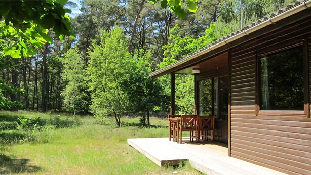 A wooden cabin with a porch and a small table.