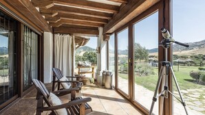 Un balcon avec des chaises en bois, une table et un télescope.