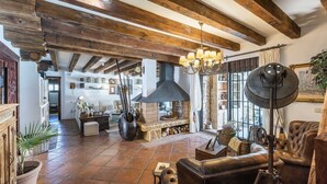 Un intérieur rustique avec des poutres apparentes, une cheminée en pierre, des meubles en cuir et une grande fenêtre.