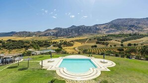 Une piscine entourée d’une terrasse, avec en toile de fond des vignobles et des montagnes.