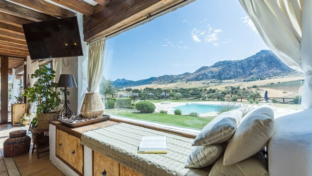 Une pièce confortable avec une grande fenêtre donnant sur une piscine et des montagnes.