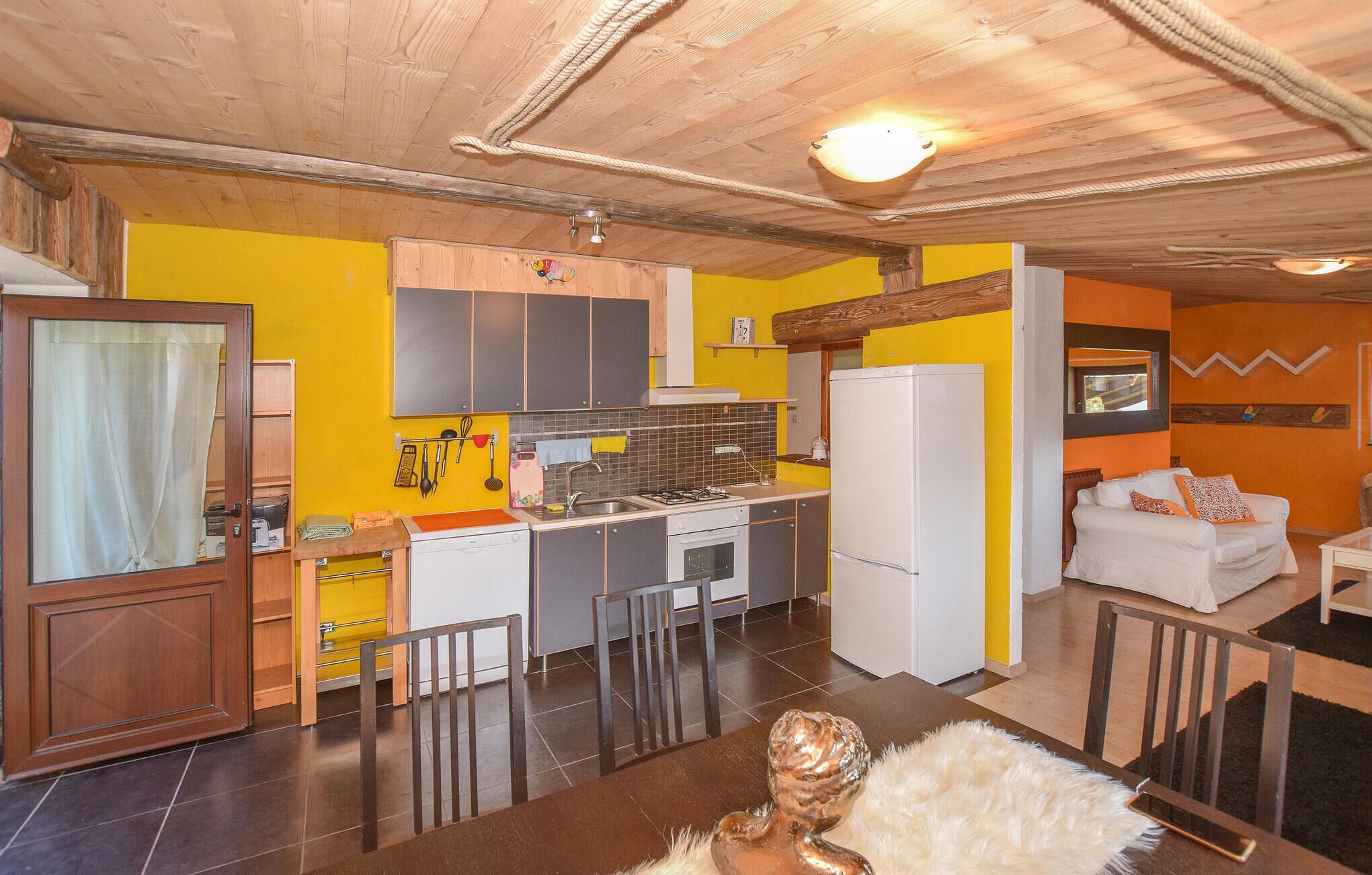 Een functionele keuken met moderne apparatuur, een eethoek met een houten tafel en stoelen, en een woonkamer met een bank en een televisie.