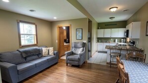 A living room with a sofa, a chair, a dining table with chairs, a kitchen area with cabinets and appliances, and a door leading to another room. - 2 Bedrooms - Room to park boat! - Close to water & Potawatomi State Park (Sturgeon Bay)