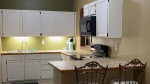 A compact kitchen with white cabinets, a microwave, and a small dining area with two chairs. - 2 Bedrooms - Room to park boat! - Close to water & Potawatomi State Park (Sturgeon Bay)