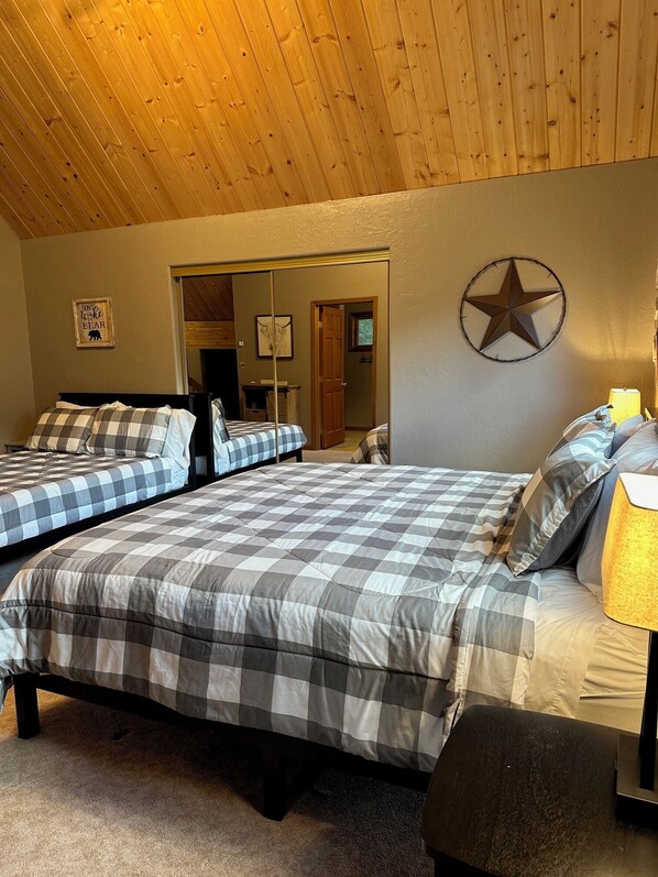 A room with two beds, a wooden ceiling, and a star decoration on the wall.