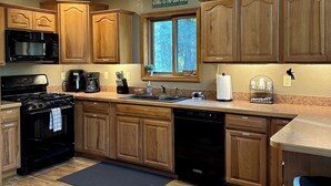 A kitchen with wooden cabinets, a stove, a microwave, and a sink.