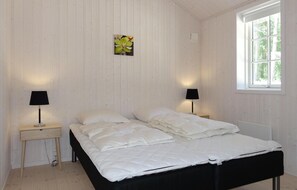 Ein Schlafzimmer mit einem Bett, zwei Nachttischen mit Lampen, einem Fenster und einem Wandbild.