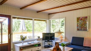 Ein gemütliches Wohnzimmer mit Fernseher, Sofa und Essbereich mit Tisch und Stühlen.