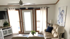 Un salon avec un canapé beige, un fauteuil blanc, une table basse agrémentée d’une plante et une lampe sur une table d’appoint.