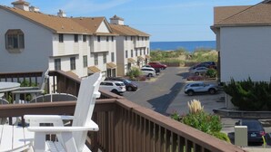 A coastal hotel with multiple-story buildings, a parking lot, and a view of the ocean.