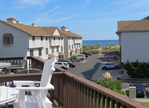 A coastal hotel with multiple-story buildings, a parking lot, and a view of the ocean.