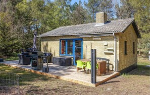 A small wooden cabin with a blue door, a patio with outdoor furniture, and a barbecue grill. - Beach front home in Aakirkeby with WiFi (Aakirkeby)