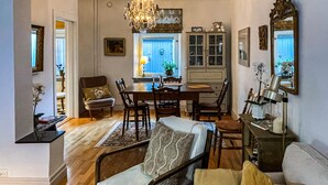 Uma área de refeições com um candelabro, móveis de madeira e uma janela com persianas azuis.