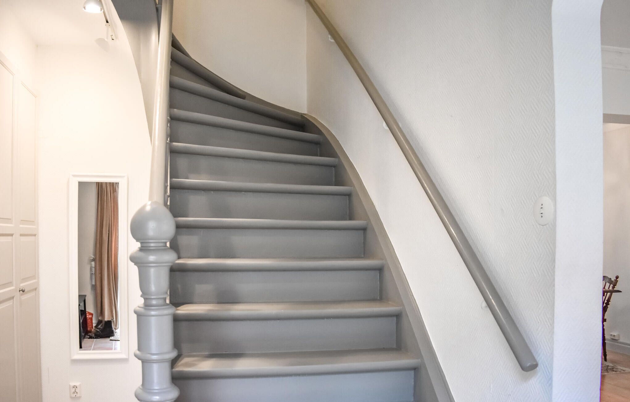 A staircase with a handrail and a door at the bottom.