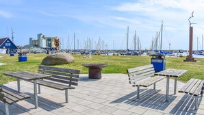 Um parque à beira-mar com bancos, uma rocha grande e uma estátua.