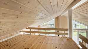 A wooden attic room with a sloped ceiling, large windows, and a wooden floor. - 2 bedroom gorgeous home in Haarby (Haarby)