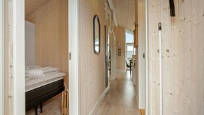A hallway with wooden walls and floors, leading to a bedroom with a bed and a radiator. - 2 bedroom gorgeous home in Haarby (Haarby)