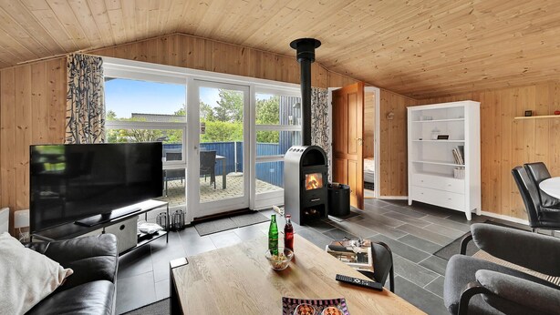 A cozy living room with a TV, seating, a fireplace, and a view of the outdoors. - 3 bedroom amazing home in Tarm (Tarm)
