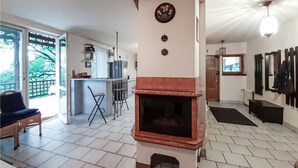 Een woonkamer met een open haard, een eethoek en een keuken op de achtergrond.
