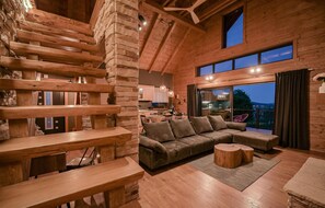 Amplia sala de estar con escalera de madera, un sofá grande y una mesa de comedor.
