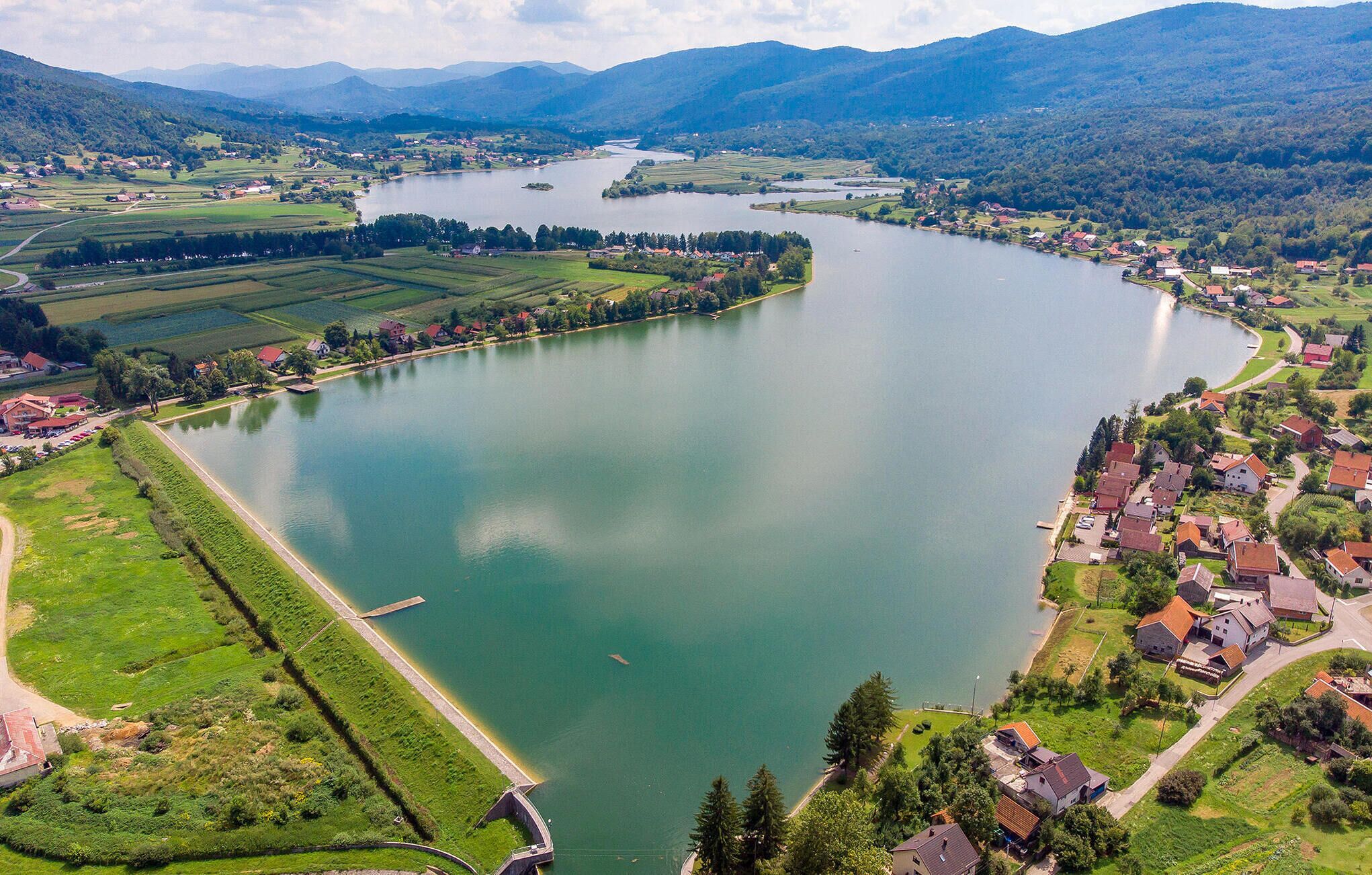 Une vue aérienne d’une rivière qui serpente à travers une ville, avec des maisons et des champs.