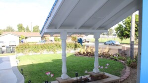 A covered patio area with a stone planter, outdoor lighting, and a view of a residential street.