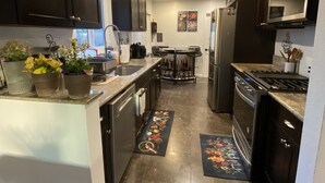 A modern kitchen with dark cabinets, stainless steel appliances, and a central island with a sink and countertop.