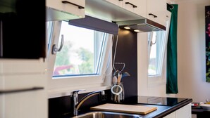 A modern kitchen with a stainless steel sink, a wooden cutting board, and a window with a view of greenery outside. - Gorgeous home in Breukelen with WiFi (Breukelen)