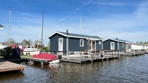 A marina with two docked boats, a covered boat, and a row of mobile homes with a dock. - Gorgeous home in Breukelen with WiFi (Breukelen)