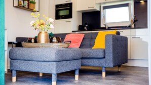 A modern living room with a grey sectional sofa, a coffee table, and a vase with flowers. - Gorgeous home in Breukelen with WiFi (Breukelen)