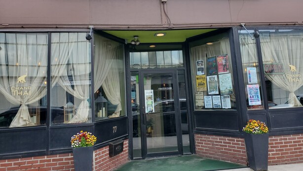Chang Thai Cafés facade med et skilt, en indgang med gardiner og blomsterkrukker.