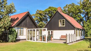 A two-story house with a red roof, a glass conservatory, and a wooden fence. - Beautiful home in Aakirkeby with WiFi (Aakirkeby)