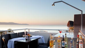 Ein Balkon mit einem Tisch für zwei Personen, einer Flasche Alkohol und einem Martini-Glas.