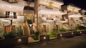Ein modernes, mehrgeschossiges Wohngebäude mit Balkonen, einer Treppe und gut beleuchteter Fassade.