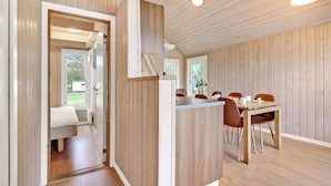 Un interno in legno con zona pranzo, una panca e una porta che dà su un balcone.
